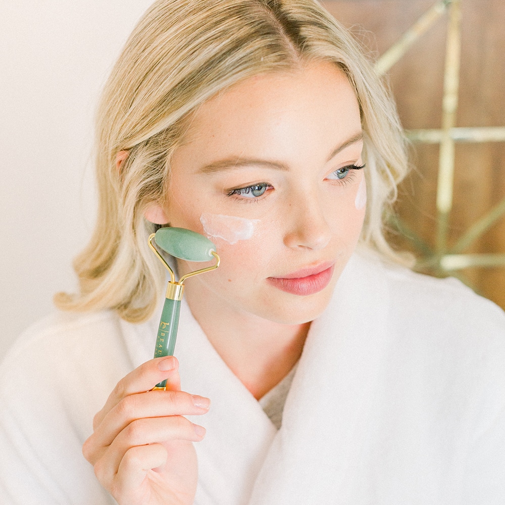 Woman with product on cheeks using a jade roller