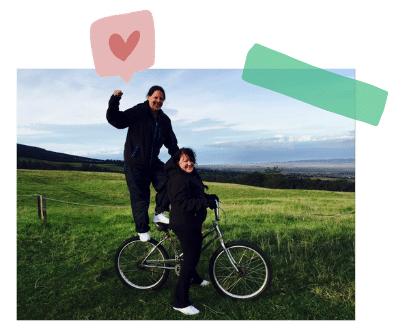 Two women posing with a bike for a picture